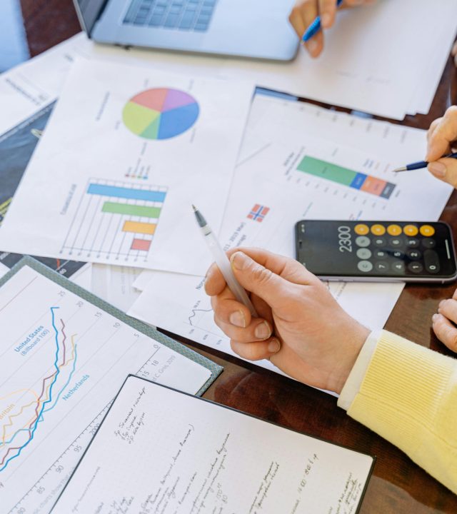 A close-up of businesspeople analyzing financial data and charts during a meeting.